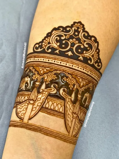 A close-up of the top part of the arm band, showing the beautiful details of the peacocks and elephants in a palace setting.