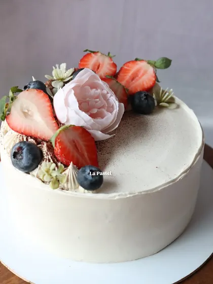 A close-up of the fresh berries and delicate flower on this simple white cake.