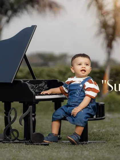 Sunny days with my sunshine. A boy in overalls enjoys a musical moment with his mini piano in the park.