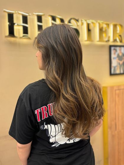 A back view of a client's long, healthy hair after a balayage service. The color adds beautiful dimension and a natural-looking glow.