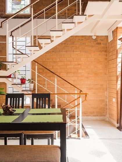 The dining area in the Vruksha home, situated next to the staircase. The open-plan layout and use of exposed brick create a warm, communal atmosphere, perfect for the three sisters who live here.