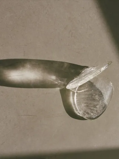 An abstract, artistic shot of the new Bocci 141 series. The play of light and shadow on the free-form glass puddle highlights its unique, organic texture and sculptural quality.
