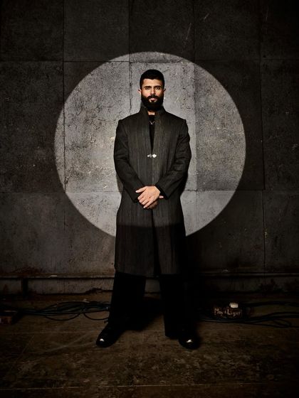 Vijay Deverakonda in a powerful, dark, structured piece by Anamika Khanna. The dramatic silhouette and spotlight create a theatrical and high-impact fashion moment.