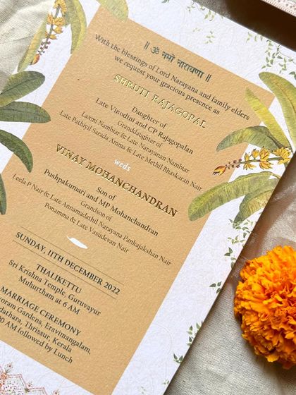 An invitation for a South Indian wedding, capturing the region's quintessential simplicity and culture. The design features banana leaves, marigolds, and elegant Sanskrit script with gold foil.