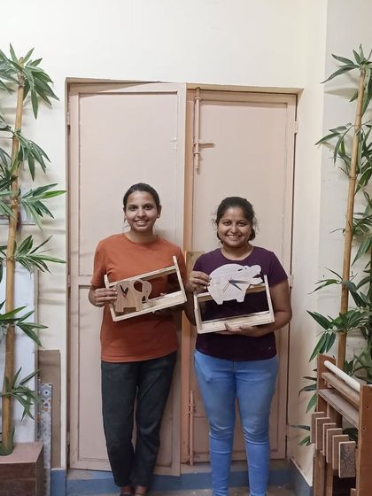Two students with the shelves they built, which feature fun elephant and pig cutouts. This is a great way to personalize a simple project.