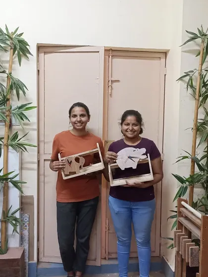 Two students with the shelves they built, which feature fun elephant and pig cutouts. This is a great way to personalize a simple project.