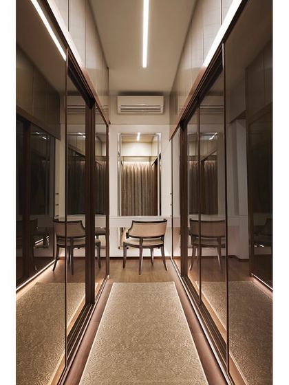 The long walk-in wardrobe was designed with mirrored glass shutters to create an illusion of a larger, more open space while providing ample storage.
