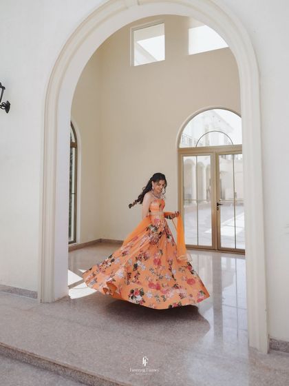 The bride twirling in her vibrant floral lehenga in a beautiful sunlit corridor. This shot is full of life, color, and movement, perfect for a Haldi celebration.