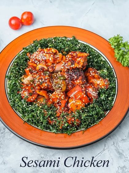 This is our Sesame Chicken. Crispy chicken is tossed in a savoury sauce and served on a bed of crispy spinach, then garnished with sesame seeds for added texture and flavour.