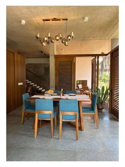 The dining room in 'Villa 34' is conceived as a pavilion within a garden, enclosed by glass and louvered wooden shutters. This design allows the space to be completely opened up, merging the act of dining with the experience of being in nature.