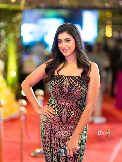 A confident pose from a guest on the red carpet, her smile and style lighting up the frame.