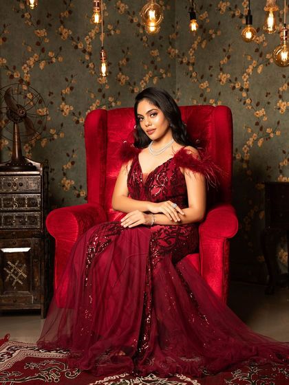 A queen on her throne. This red gown, with its sparkling sequins and dramatic feather details, is perfect for making a powerful and elegant statement.