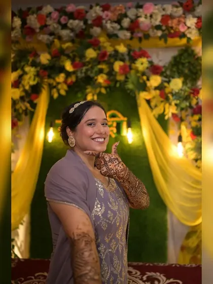 The joy of a Mehendi ceremony captured in front of our festive decor. The green grass wall contrasts beautifully with the yellow drapes and colorful flowers, making the bride stand out.