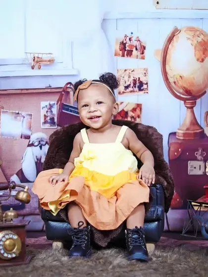 A sweet, smiling portrait of a baby girl in our vintage traveler studio.