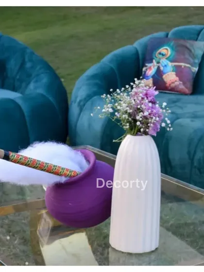 Themed decor details, including a pot of "butter" and a flute (bansuri) on a coffee table with Krishna-themed cushions.