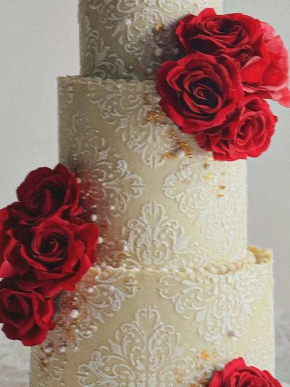 A detailed shot of the stencil work on our ivory and red rose wedding cake. The delicate pattern adds a layer of sophistication and texture.