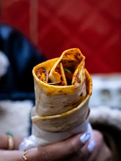A famous Istanbul street food, the durum wrap, held in hand. This shot captures the authentic, on-the-go experience.