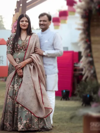 Elegance for a daytime celebration. This custom floral satin print anarkali is hand-highlighted with delicate french knots and beads, paired with a light organza dupatta for a soft, romantic feel.