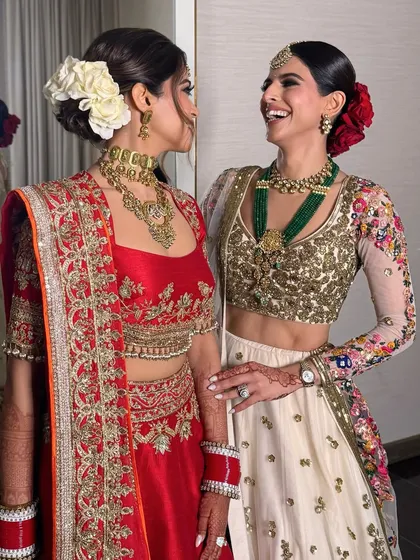 Two brides, one with a white rose bun and the other with a red rose bun, showcasing different takes on the classic floral updo.