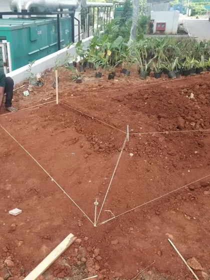 Site work begins with precision. Here, strings are used to mark out the exact geometry of a sculpted ground mound, translating the design from paper to earth.