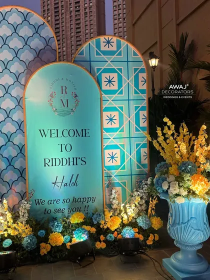 The welcome area at night, with spotlights highlighting the vibrant colors of the flowers and the intricate patterns of the decor.