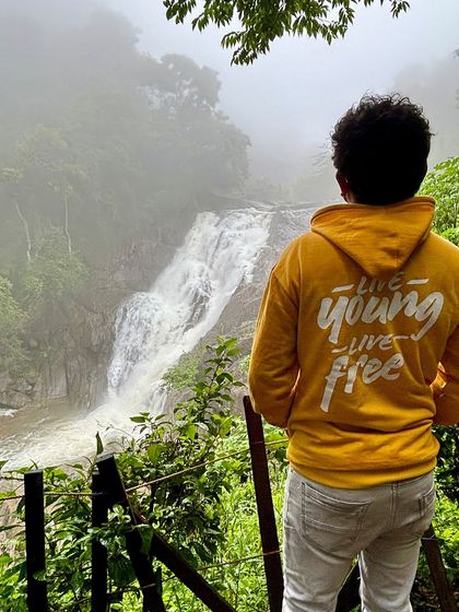 "Live Young, Live Free" - the message on our hoodie perfectly captures the spirit of this moment at a waterfall in Wayanad.