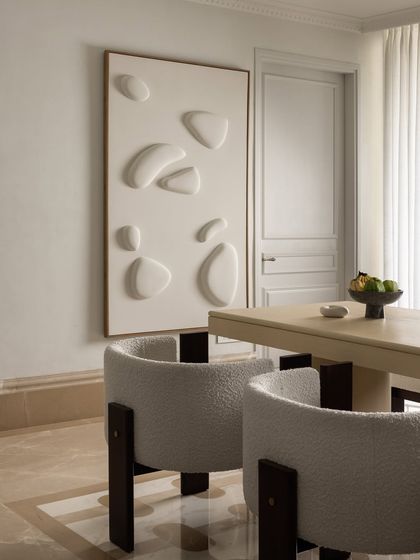 In the dining room at Ecru Maison, we paired soft boucle chairs with a minimalist dining table to create a sense of understated luxury. A large-scale textured wall relief adds an artistic, sculptural dimension to the serene space.