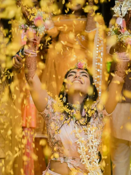 A bride raises her hands in joy as she is showered with flower petals. This is a moment of pure bliss, captured from a low angle to make it feel even more epic.