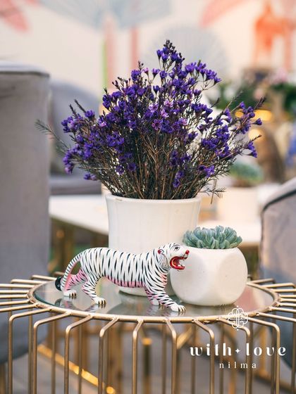 A small detail from 'The Conservatory' baby shower, featuring a miniature white tiger figurine among the floral arrangements.