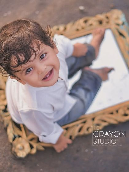 A creative, top-down view of a smiling boy with his reflection in a mirror on the sand. This artistic portrait captures his curious and happy nature in a unique way.