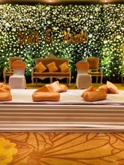A close-up of a beautiful floral wall stage. The mix of white flowers and green leaves, combined with soft lighting, creates a lush and romantic backdrop.