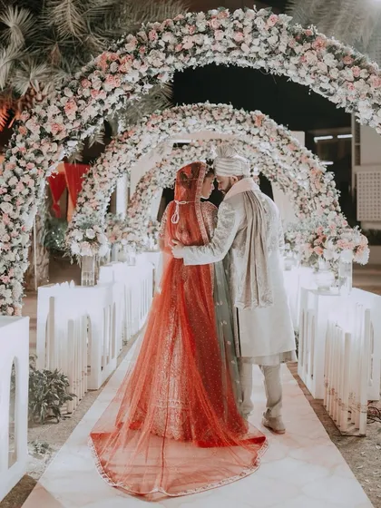 A tender moment under the floral arch. We frame our couples within the beautiful decor of their wedding, creating stunning portraits that are full of love and celebration.