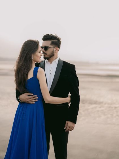 A stylish couple posing by the sea. The contrast of the royal blue gown against the groom-to-be's classic black tuxedo makes for a sharp and modern pre-wedding look.