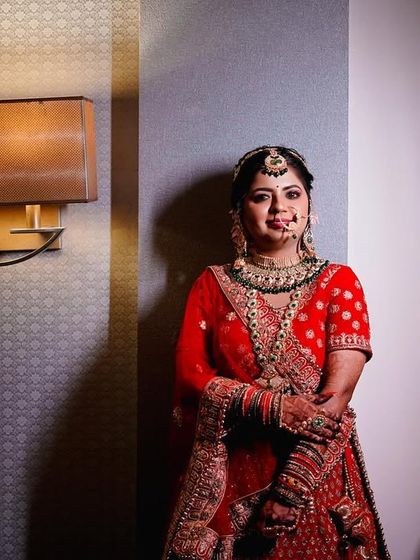 A full-length portrait of the bride in her stunning red lehenga. The dramatic side lighting creates a sophisticated and elegant look, highlighting the rich texture of her outfit. (Similar to 56)
