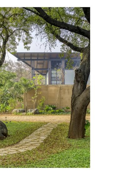 A winding path leads to the house, framed by existing trees. The design works with the site's natural contours and flora, creating a journey rather than just an entrance.