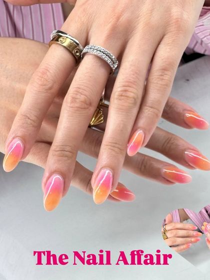 A warm, sunset-inspired ombré, blending from a vibrant pink to a sunny orange on almond-shaped nails.