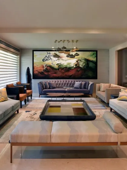 The formal living area in the renovated Delhi home, centered around a powerful piece of art. The symmetrical arrangement of sofas in soft, cool tones creates a balanced and harmonious space for conversation and relaxation.
