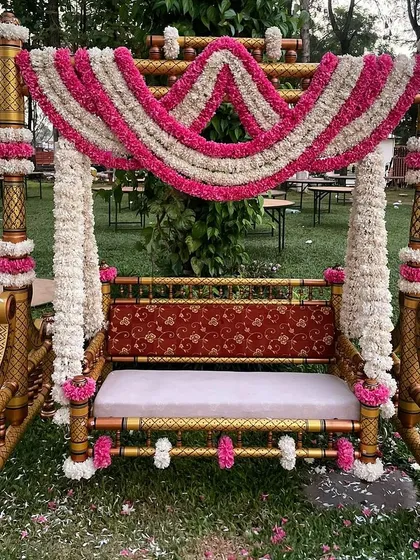 A traditional Oonjal (swing) decorated with pink and white floral garlands, ready for the fun and significant swing ceremony in a Tamil Brahmin wedding.