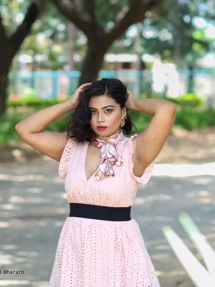 An outdoor portrait of the model in the pink dress, this time styled with a neck scarf. The natural lighting is soft and flattering.