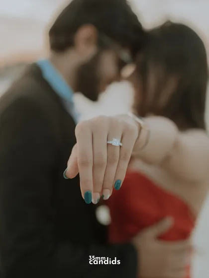 A close-up on the engagement ring, with the couple embracing softly in the background. A classic and beautiful way to announce an engagement.