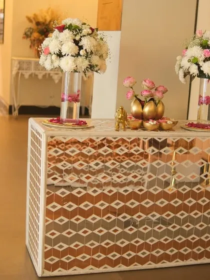 A stylish mirror console table at the entrance, decorated with tall floral arrangements and other decorative items. This piece adds a touch of modern glamour to the wedding decor.