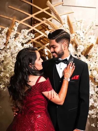 A classic reception portrait. The couple's pose is elegant and their connection is clear, set against a beautiful floral backdrop.