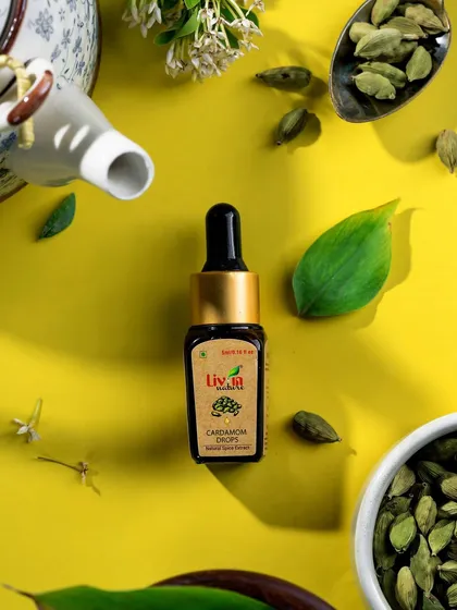 A vibrant flat lay for Livin Nature's cardamom drops. The bright yellow background makes the product pop, while the scattered cardamom pods and green leaves instantly communicate its natural, potent flavor.