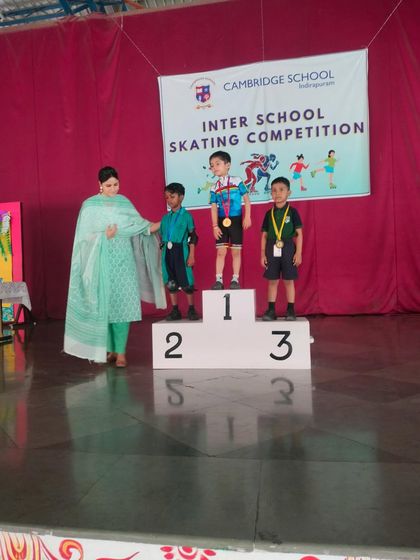 A teacher adjusts a medal for one of our skating champions, a heartwarming moment of recognition for his hard work.