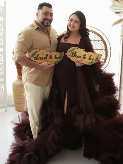 "Mom to be" and "Dad to be". This couple holds up cute signs, adding a fun and personal touch to their glamorous gown photoshoot.