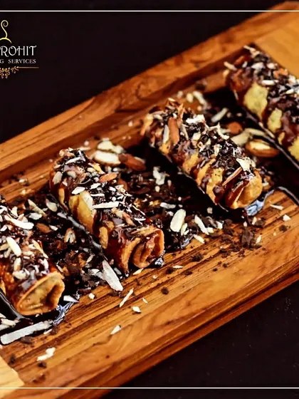 These chocolate-filled pastry rolls are a delightful Western-style dessert. They are drizzled with chocolate sauce and sprinkled with nuts for a crunchy, indulgent finish.