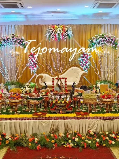 A traditional engagement plate decoration with a backdrop of white branches and flowers. The setup includes custom bride and groom trays.