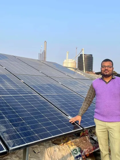 A proud member of the school administration in Begusarai stands with the newly installed solar panels. Our solutions empower educational institutions to invest their savings back into student development.