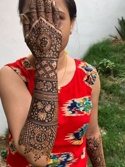 A creative pose showing off the full arm mehendi with the initial 'S' beautifully displayed.