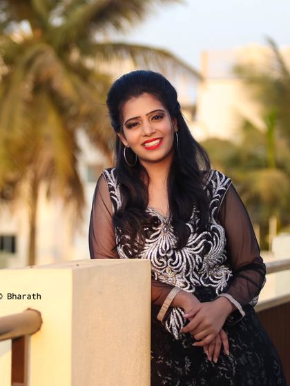 A relaxed pose on a balcony during sunset. The palm trees in the background add to the warm, evening atmosphere.